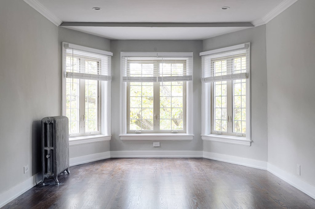 an empty room with three windows and a radiator