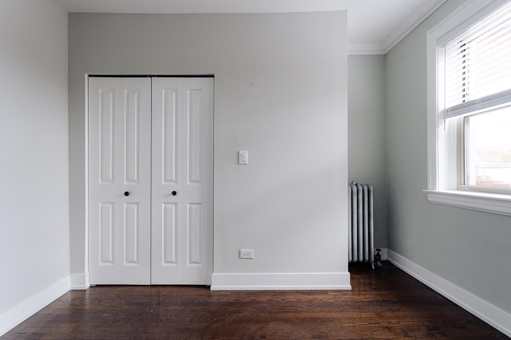 a room with two doors and a wood floor and a radiator