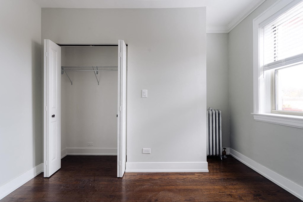 a room with a closet and a window and a wood floor