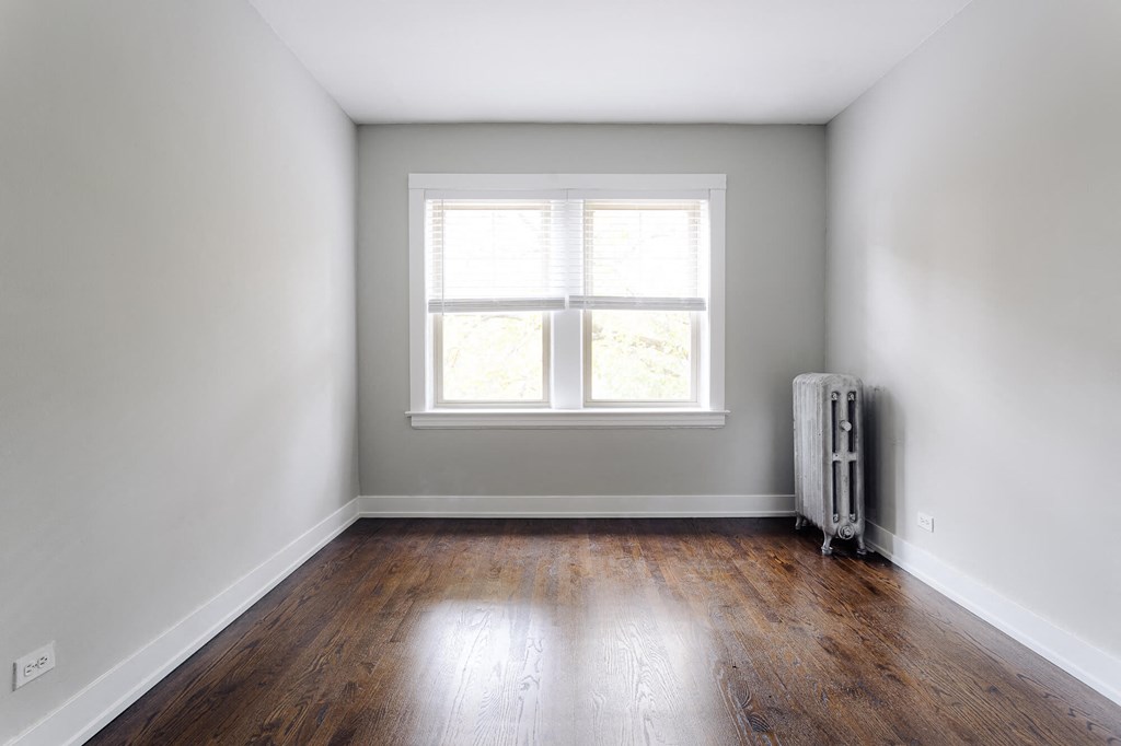 an empty room with wooden floors and a window