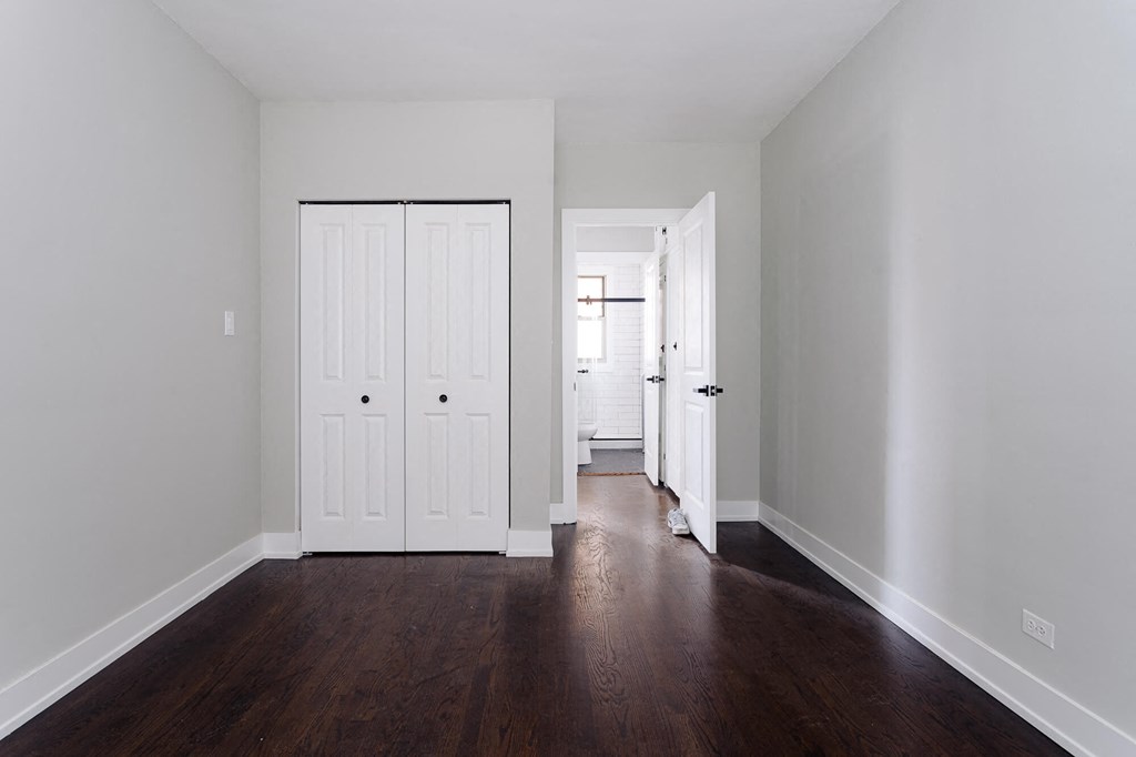 a room with white walls and wooden floors and two doors