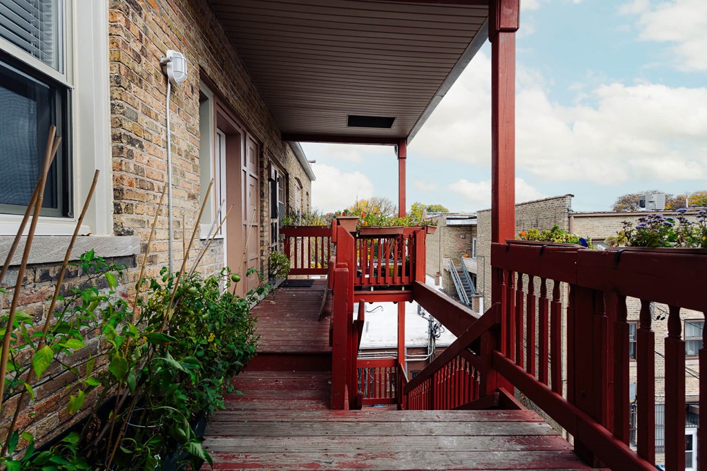 a view of a porch with red stairs and a brick building