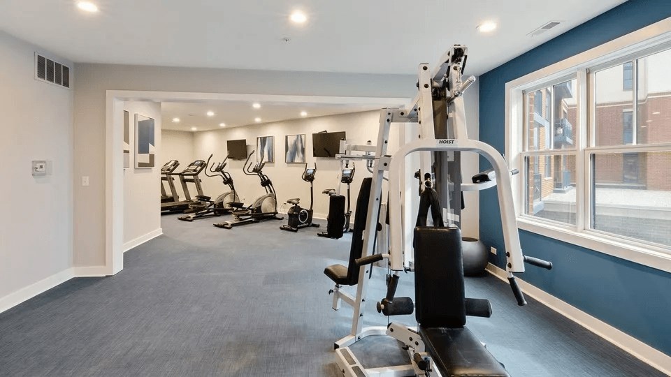 A spacious gym with a variety of equipment including treadmills, stationary bikes, and weight machines.
