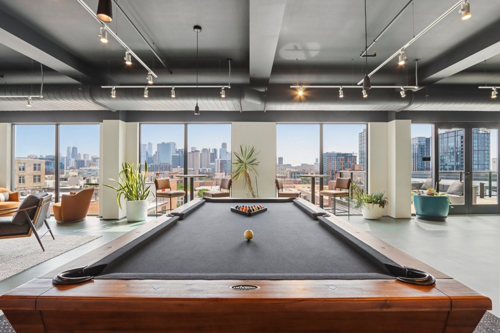 A pool table in a room with a city view.
