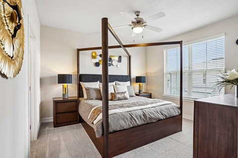 A bedroom with a large bed and a ceiling fan.