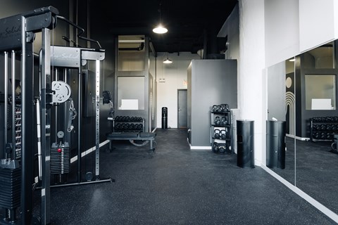 A gym with a weightlifting machine on the left and a bench press on the right.