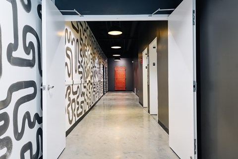 A hallway with a black and white wall on the left and a red wall on the right.
