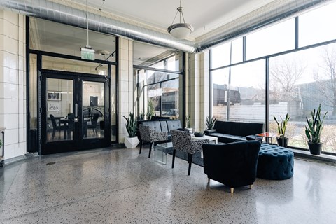 A black chair with a white patterned cushion is in the middle of a room with a glass door.