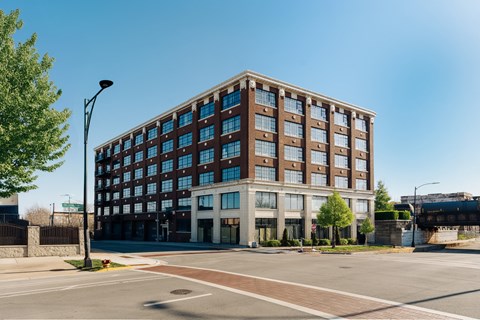A large brown building with many windows is situated on a street corner.