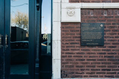 A plaque on a brick wall with a black background and white lettering.