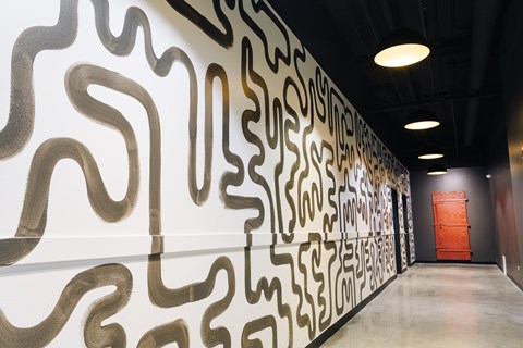 A hallway with a black and white patterned wall and a red door at the end.