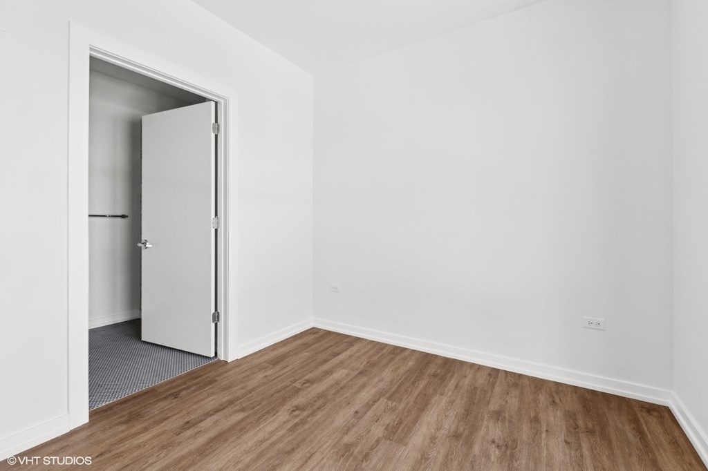 A room with a white door and a wooden floor.
