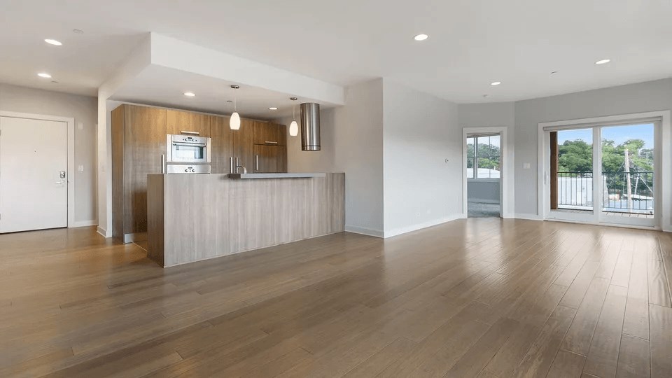 A spacious kitchen with wooden floors and white walls.