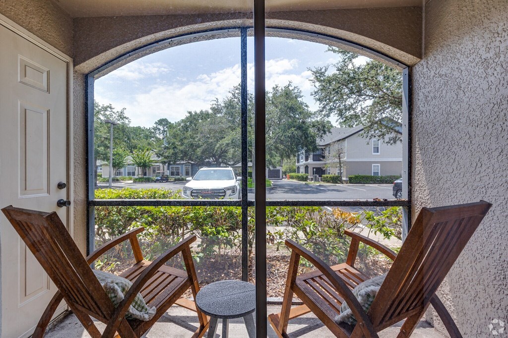 Two wooden chairs are placed on a patio with a view of the street.