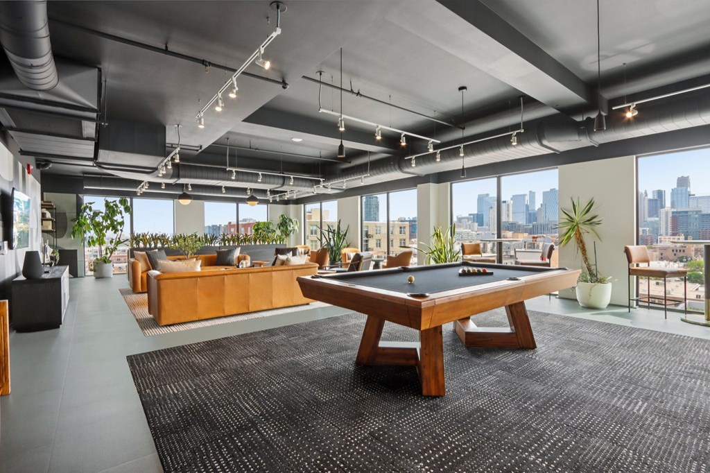 A room with a pool table and a view of the city.