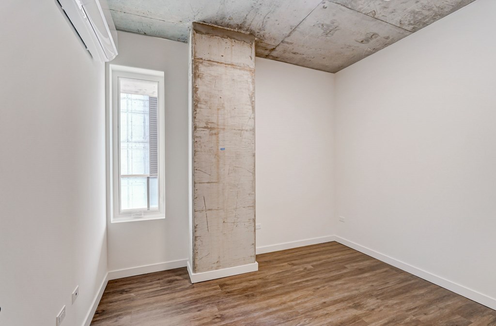 A room with a window and a pillar in the middle.