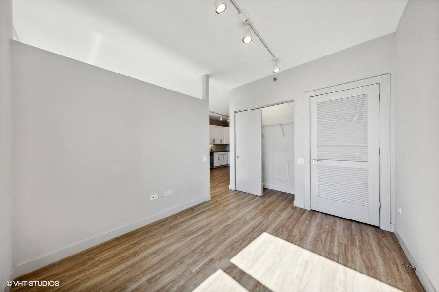 an empty living room with a door to the kitchen