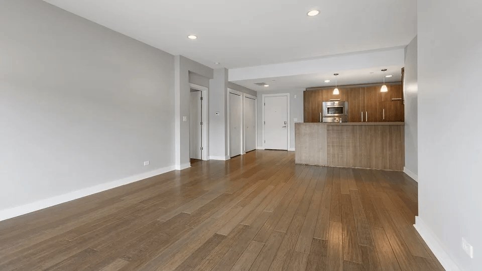 A spacious room with wooden flooring and white walls.