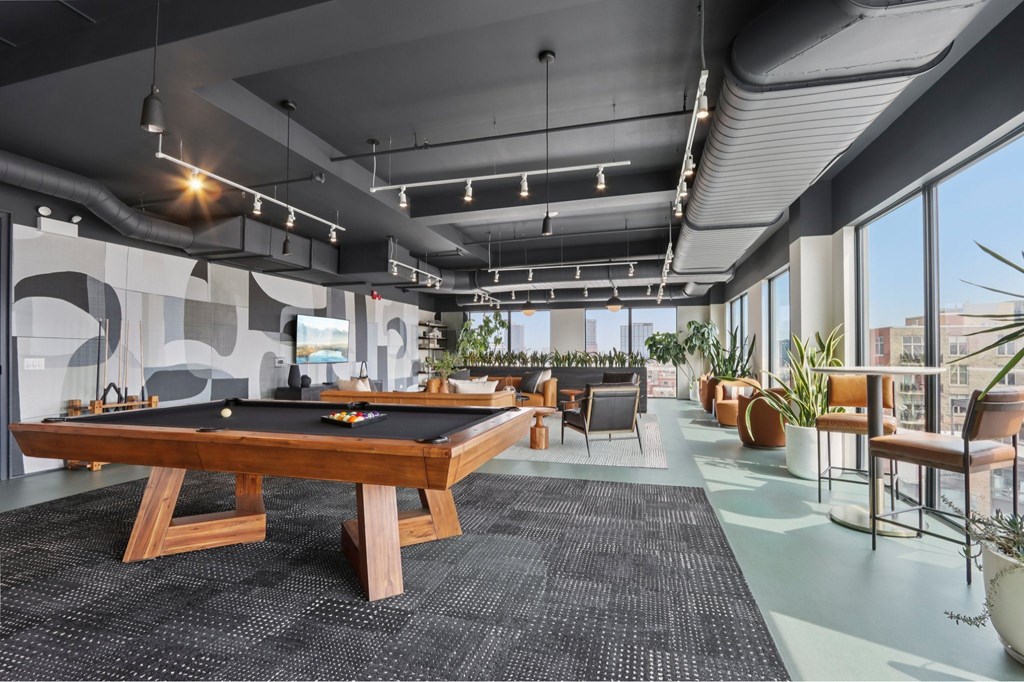 A pool table is in the middle of a room with a black carpet.