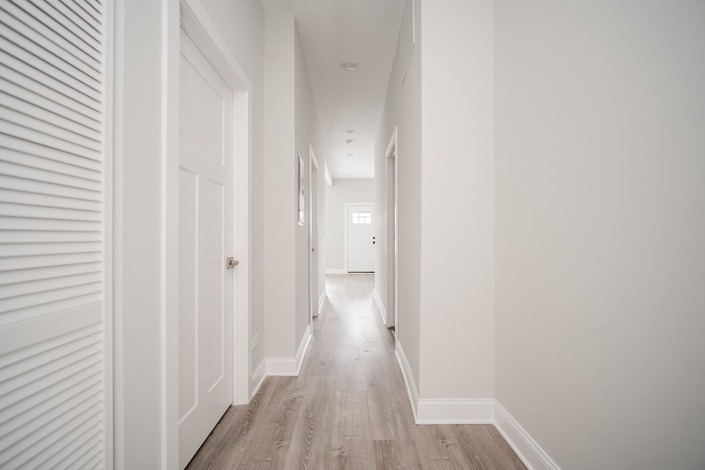 a hallway with white walls and wooden floors and white doors