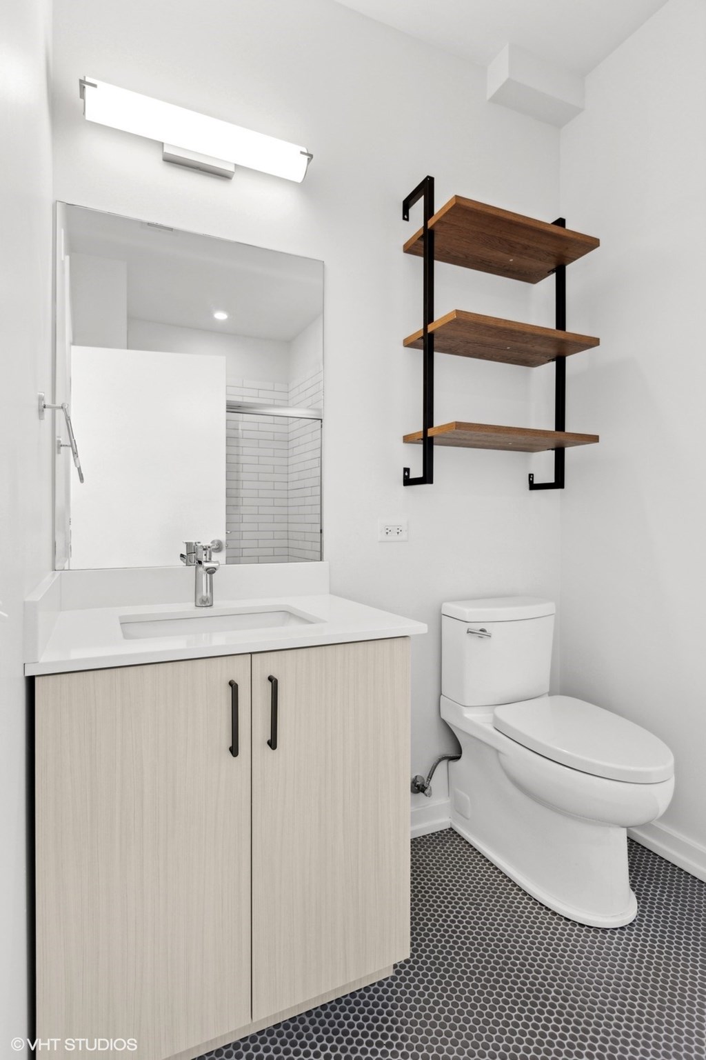A white toilet sits under a mirror in a bathroom.