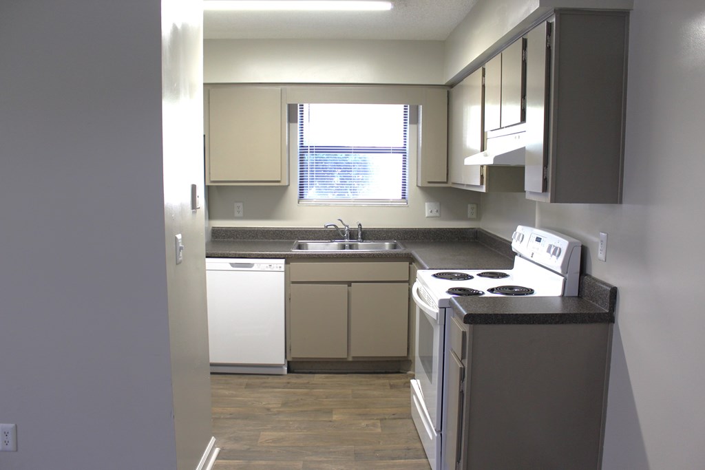 A kitchen with a white dishwasher and white oven.