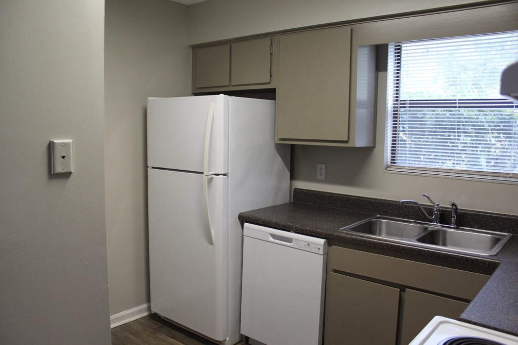 A white refrigerator is in a kitchen next to a dishwasher and a sink.