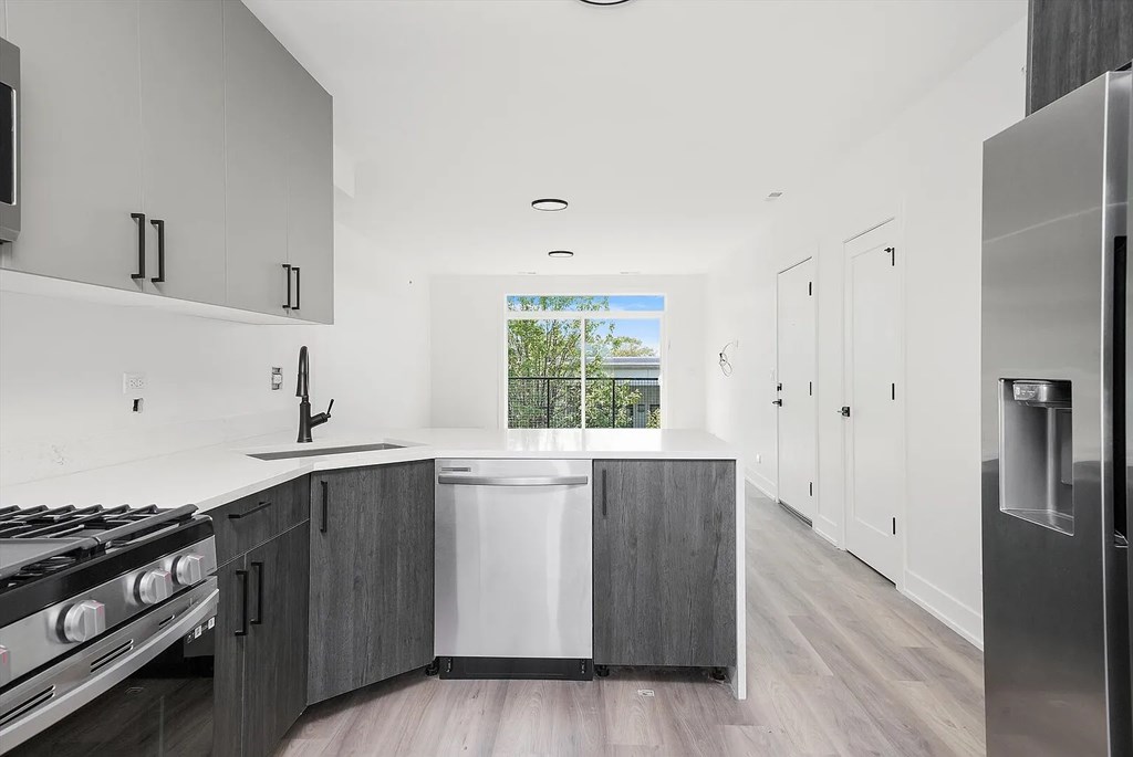 A modern kitchen with a stove, sink, and refrigerator.