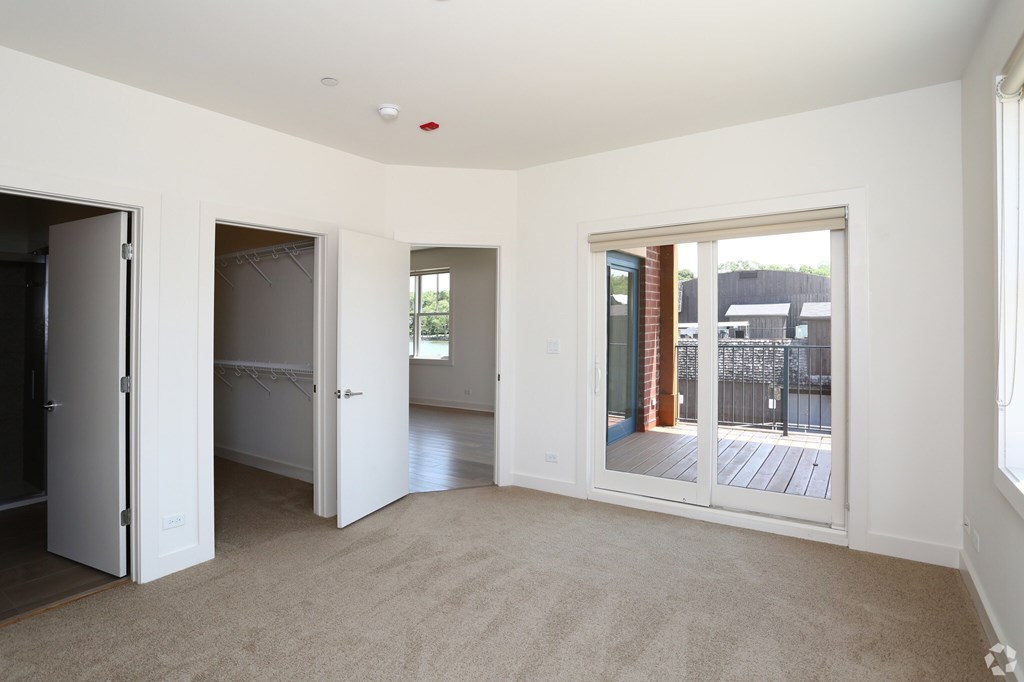 A room with white walls and carpeted floor with a sliding glass door.