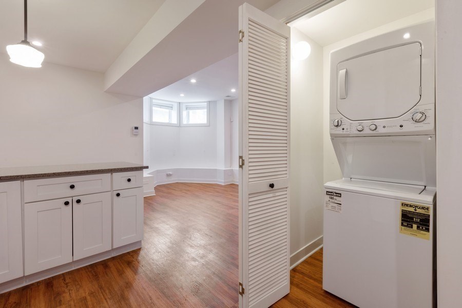A white fridge in a kitchen with wooden floors.