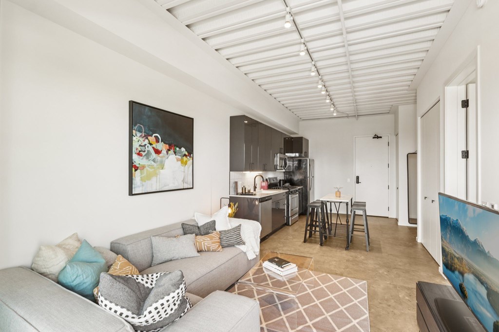 A living room with a grey couch and a painting on the wall.
