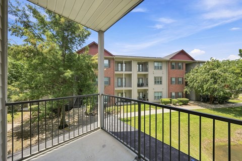 A balcony overlooks a grassy area and apartment buildings.