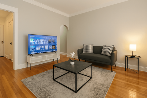 A living room with a black couch, a television, and a coffee table.