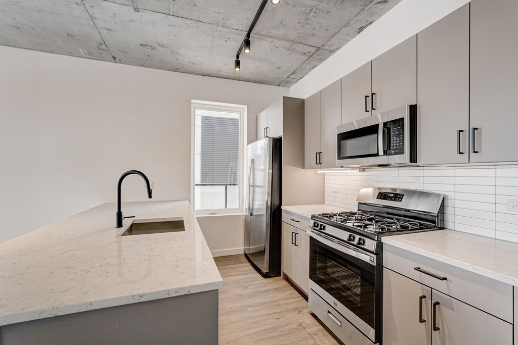 A kitchen with a white countertop and stainless steel appliances.