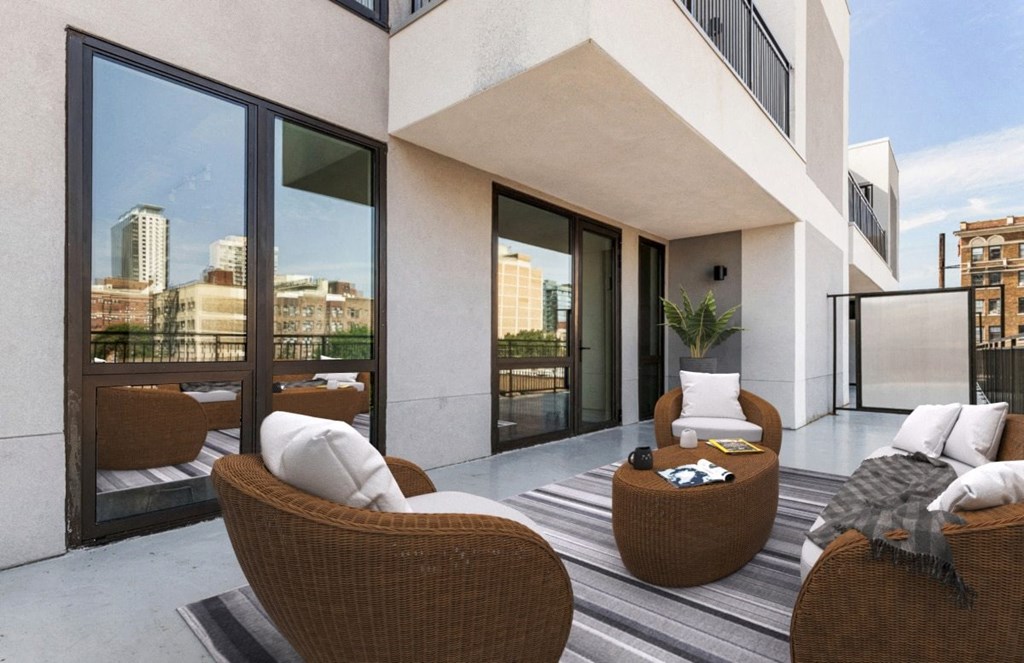 a balcony with a view of the city and a couch and chairs