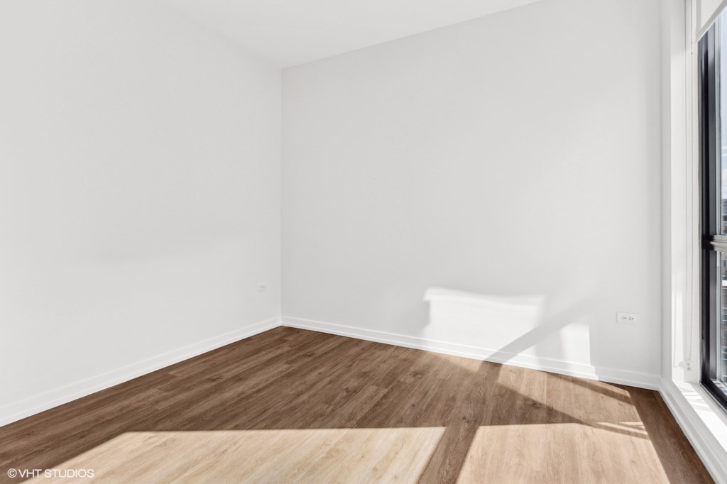 A room with wooden flooring and a window on the right side.