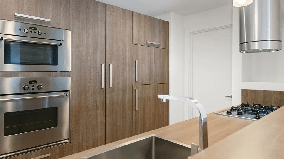 A modern kitchen with a stainless steel oven and wooden cabinets.