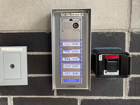 A brick wall with a meter and a switch.