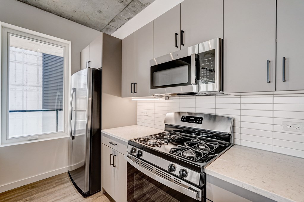 A kitchen with a stove, refrigerator, and microwave.