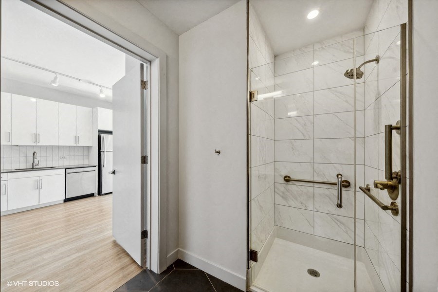 a white bathroom with a shower and a kitchen