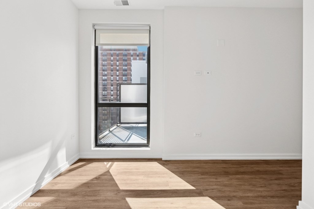 A room with a window showing a view of a building.