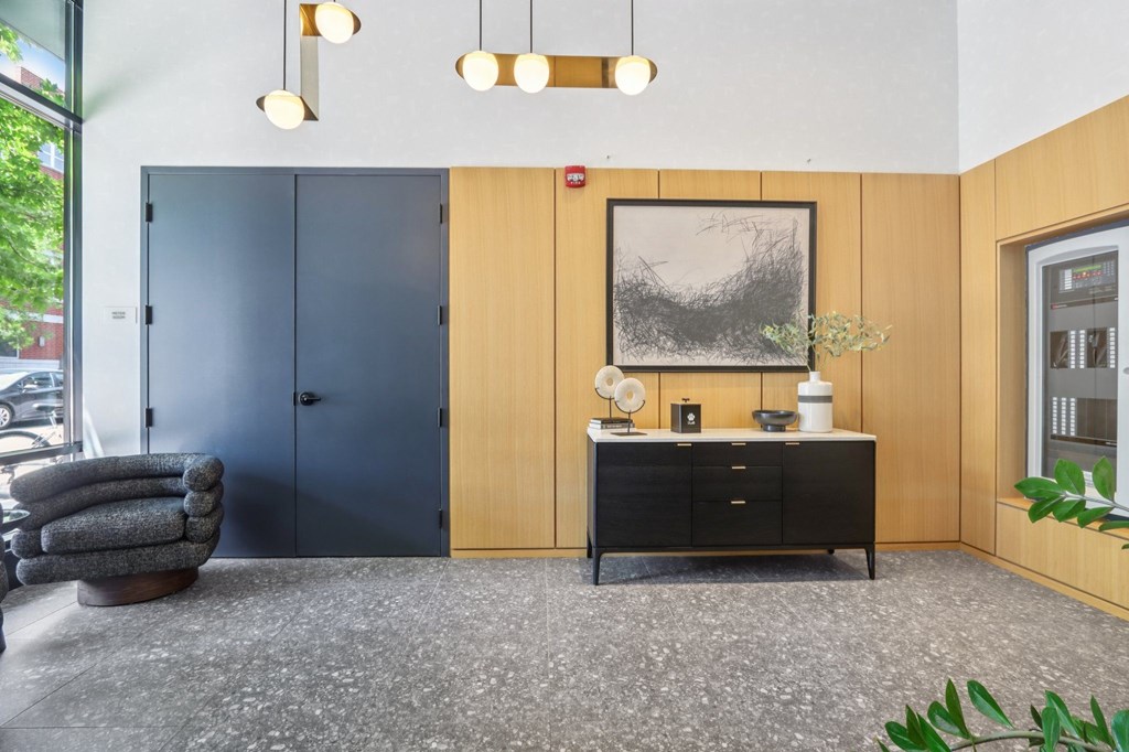 A room with a grey carpet and a wooden cabinet with a framed picture above it.