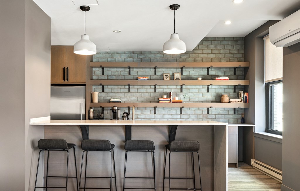 a kitchen with a bar and stools in front of a brick wall