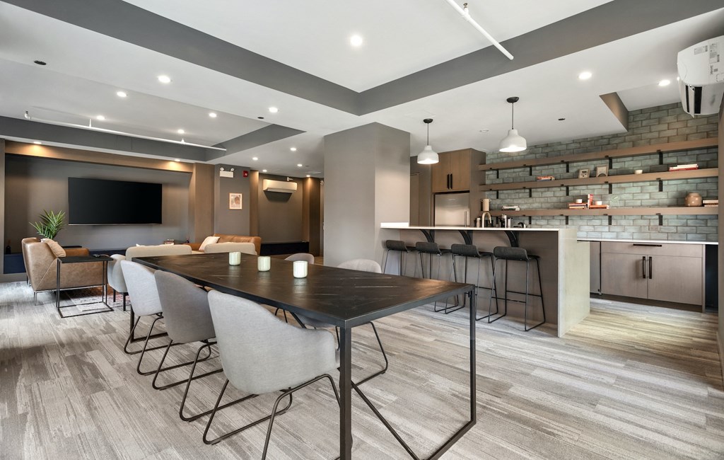 a communal area with a table and chairs and a kitchen