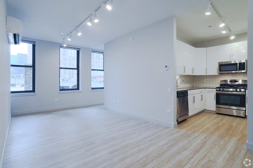 an empty living room and kitchen with white walls and wood floors