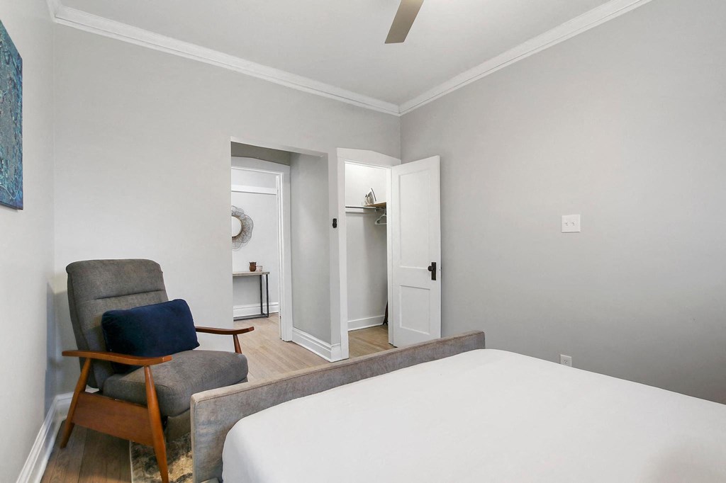 a bedroom with a bed and a chair and a door to a bathroom