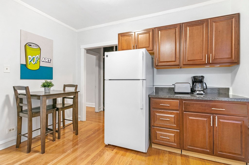 a kitchen with wooden cabinets and a table and a refrigerator