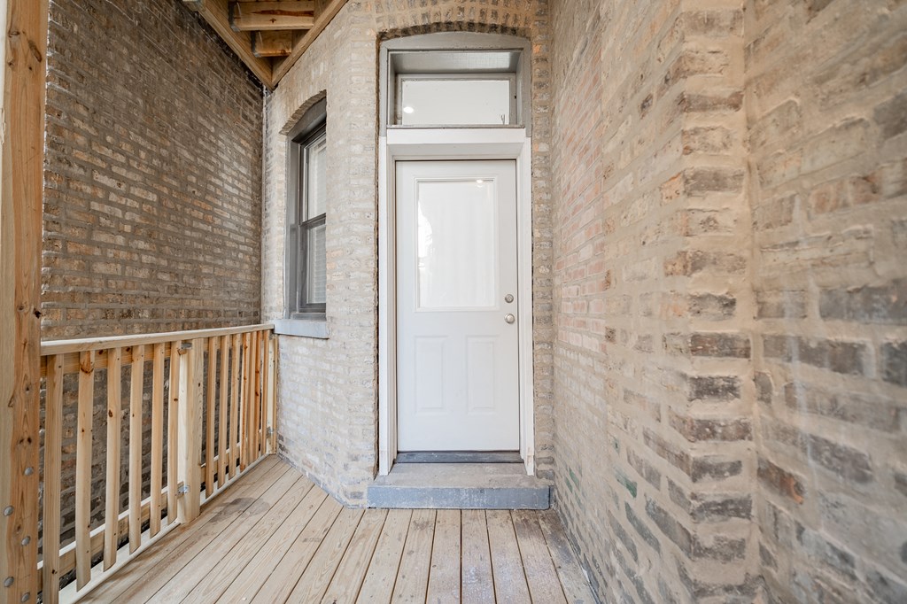 the front porch of a brick house with a white door