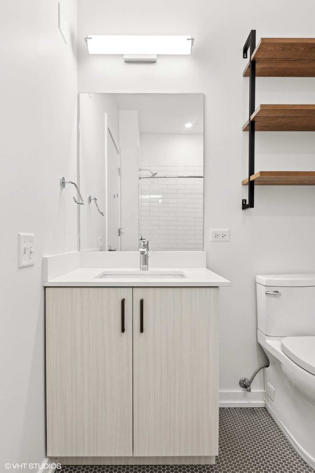 A white sink with a wooden cabinet and a white toilet.