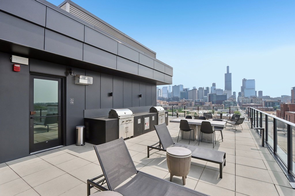 A balcony with chairs and a table overlooking a city skyline.